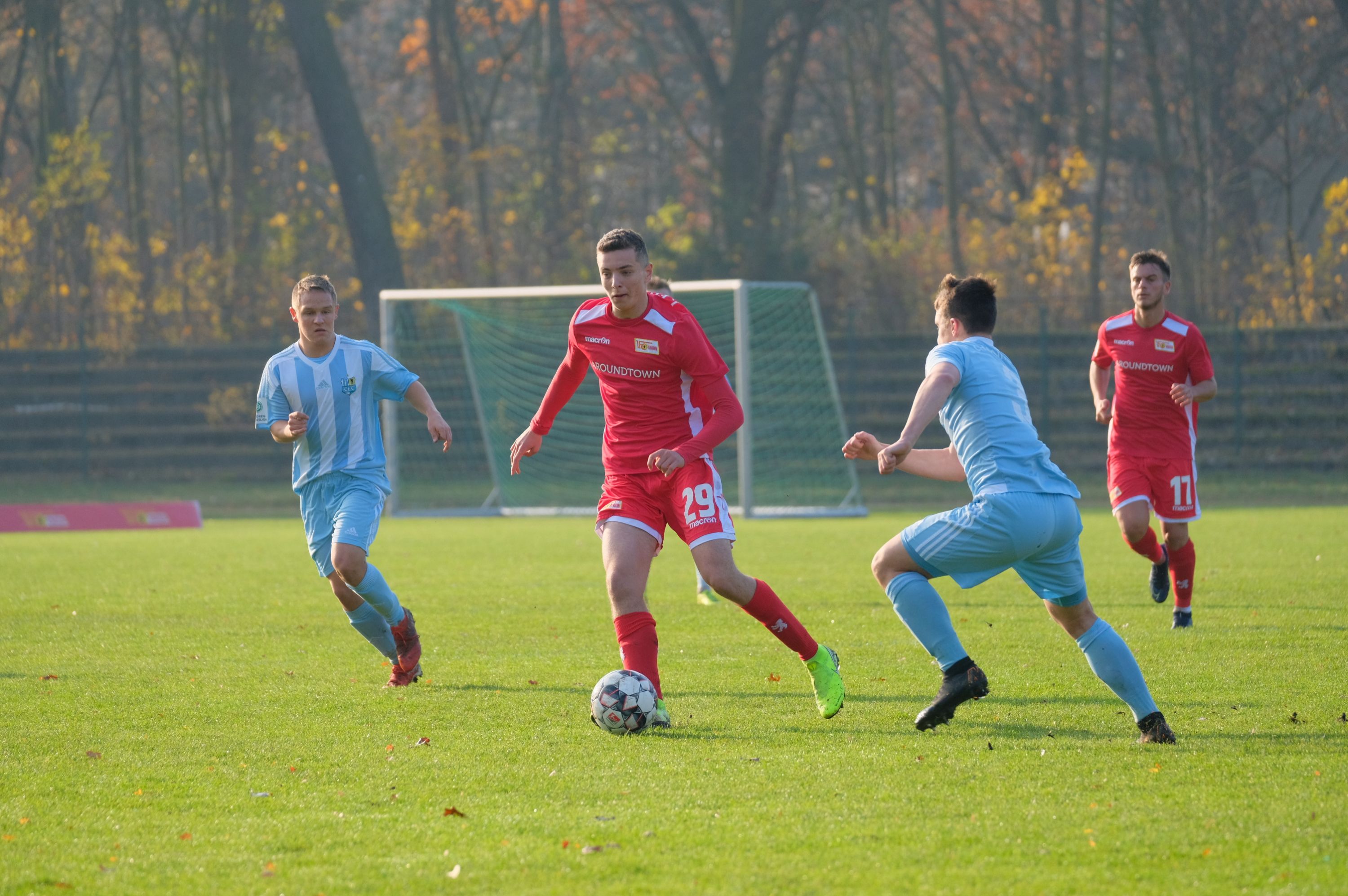Zwei Gruppen Fußballspieler spielen auf dem Rasen. Die Spieler tragen rote und blaue Trikots.