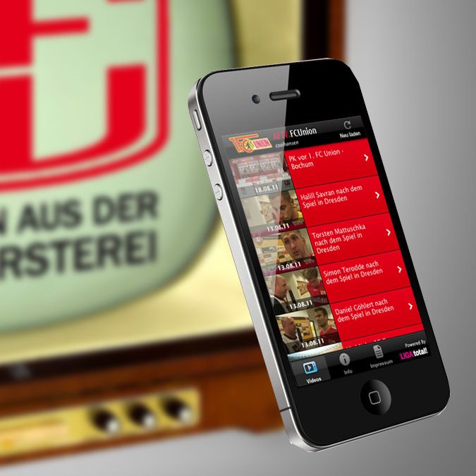 Ein Smartphone zeigt eine App mit Videos über den 1. FC Union Berlin vor einem alten Fernseher.