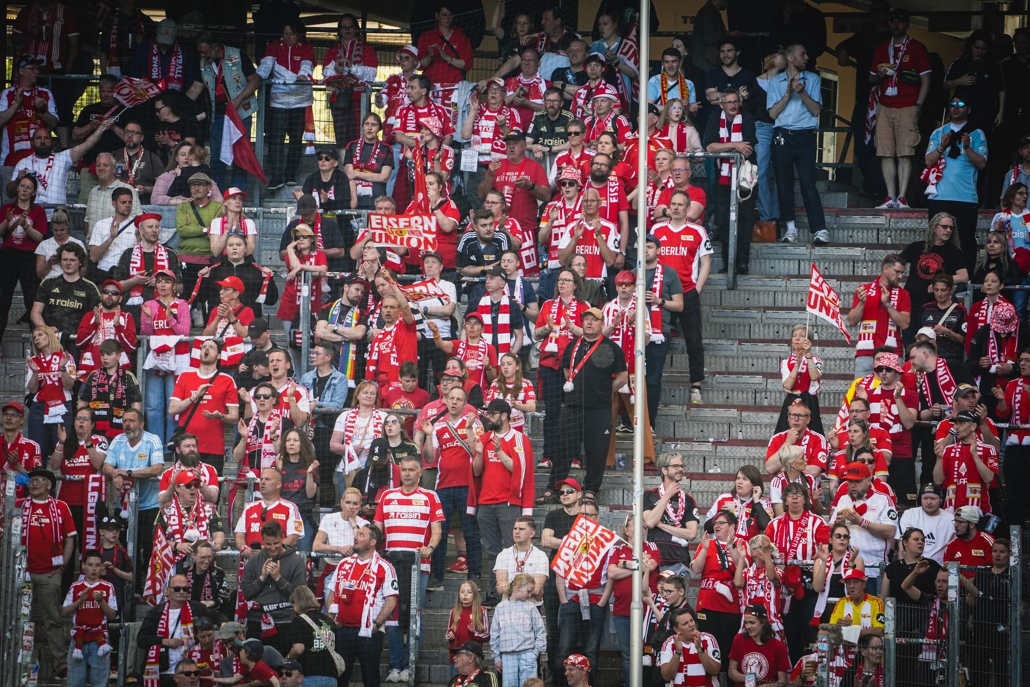 Eine Menschenmenge von Fans in roten und weißen Trikots und Schals feiert in einem Stadion.
