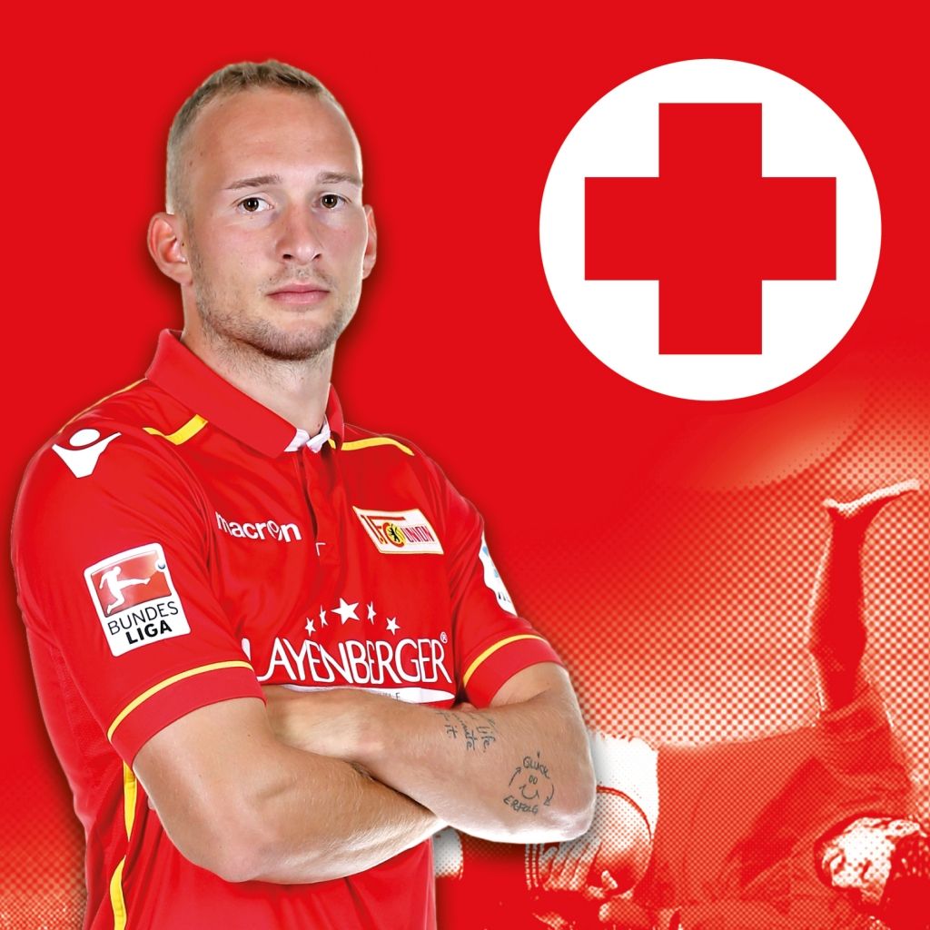 Ein sportlich gekleideter Mann posiert vor einem roten Hintergrund mit einem weißen Kreuz und Sportmotiven.