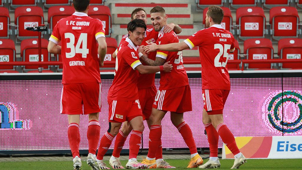 Die Fußballspieler von 1. FC Union freuen sich. Sie haben ein Tor gemacht. Viele Teamkollegen sind bei ihnen. Alle jubeln im Stadion.