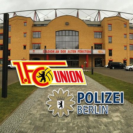 Gebäude des Stadions An der Alten Försterei mit Logos von 1. FC Union und Polizei Berlin im Vordergrund.
