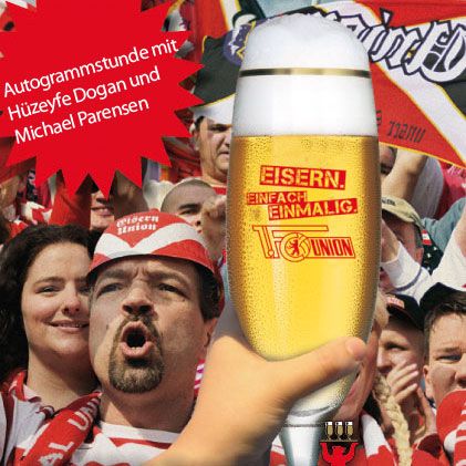 Ein Mann mit einem Schal feuert eine Fußballmannschaft an, während ein Glas Bier mit einem Union Berlin-Logo im Vordergrund zu sehen ist.