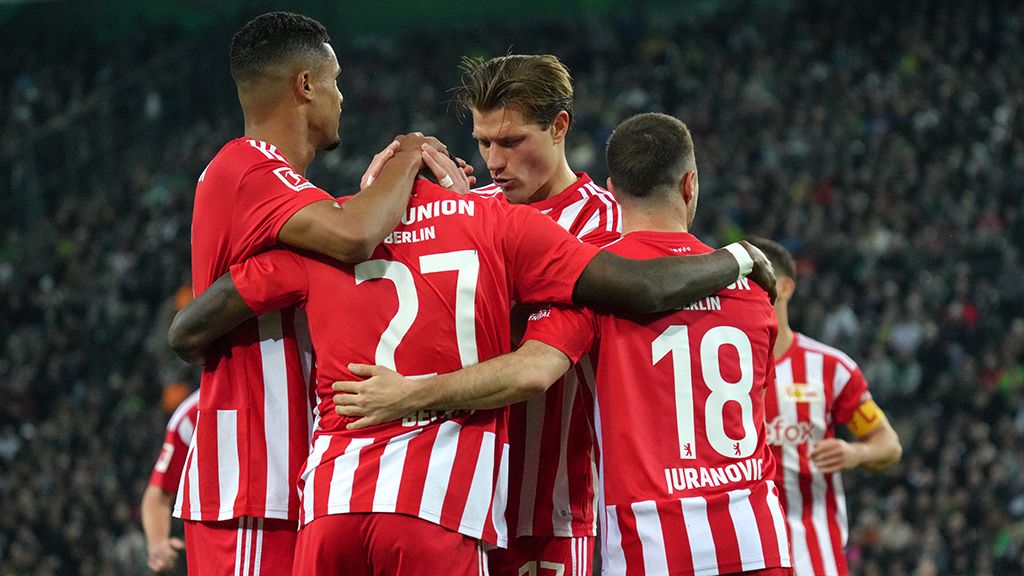 Spieler von Union Berlin umarmen sich nach einem Tor, in roten Trikots, mit Emotionen auf dem Spielfeld.