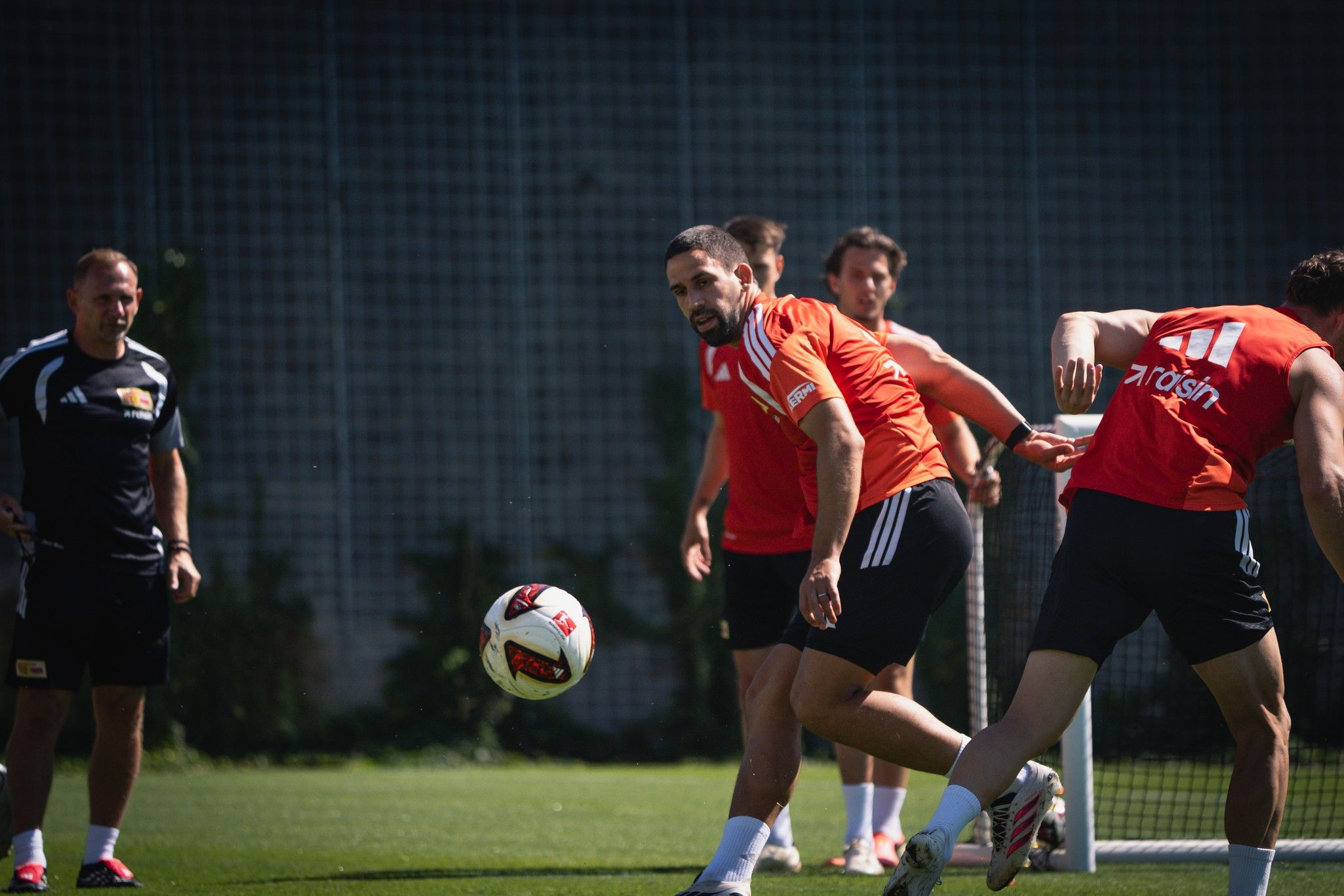 Fussballtraining mit Spielern in orangen und schwarzen Trikots, die den Ball auf einem Trainingsplatz spielen.
