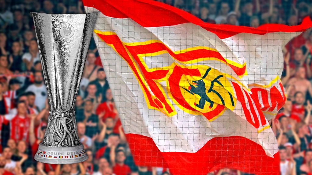Pokal der UEFA Europa League neben einer Fahne des FC Union Berlin mit ihrem Logo und einer begeisterten Menschenmenge im Hintergrund.