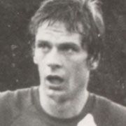 Ein schwarz-weißes Porträt eines besorgten männlichen Sportlers mit kurzem Haar, der eine Sportkleidung trägt.