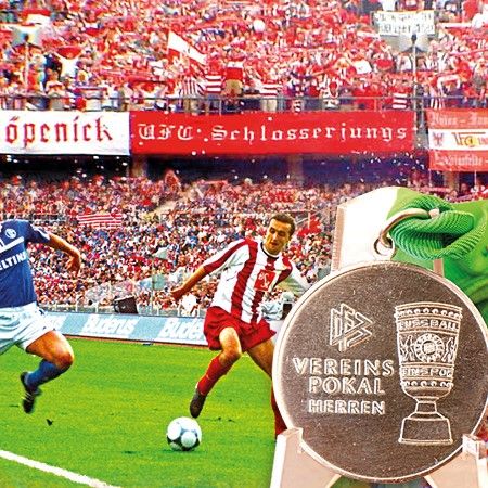 Ein Fußballspiel mit Spielern in roten und blauen Trikots, im Hintergrund jubelnde Fans und eine Medaille mit der Aufschrift "Vereinspokal Herren".