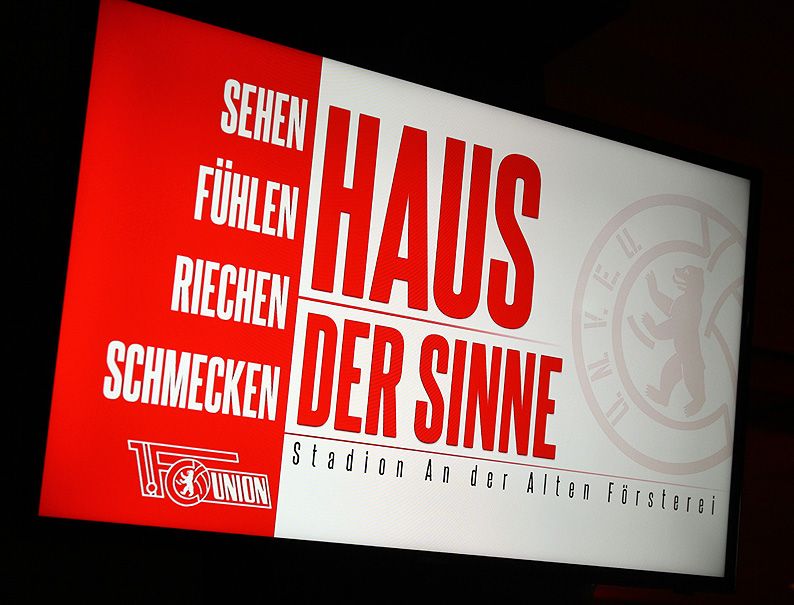 Bild eines Plakats mit dem Text "Sehen, Fühlen, Riechen, Schmecken" und der Überschrift "HAUS DER SINNE", Stadion An der Alten Försterei.