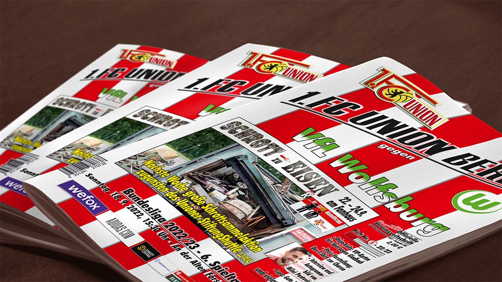 Drei Exemplare einer Sportzeitschrift mit dem Titel "1. FC Union Berlin gegen VfL Wolfsburg" auf einem Tisch.