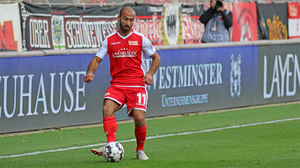 Ein Fußballspieler in rotem Trikot steht an der Seitenlinie und bereitet sich darauf vor, den Ball zu spielen.