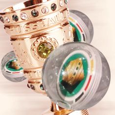 Goldener Pokal mit grünen und klaren Kristallen, umgeben von runden, farbigen Objekten.