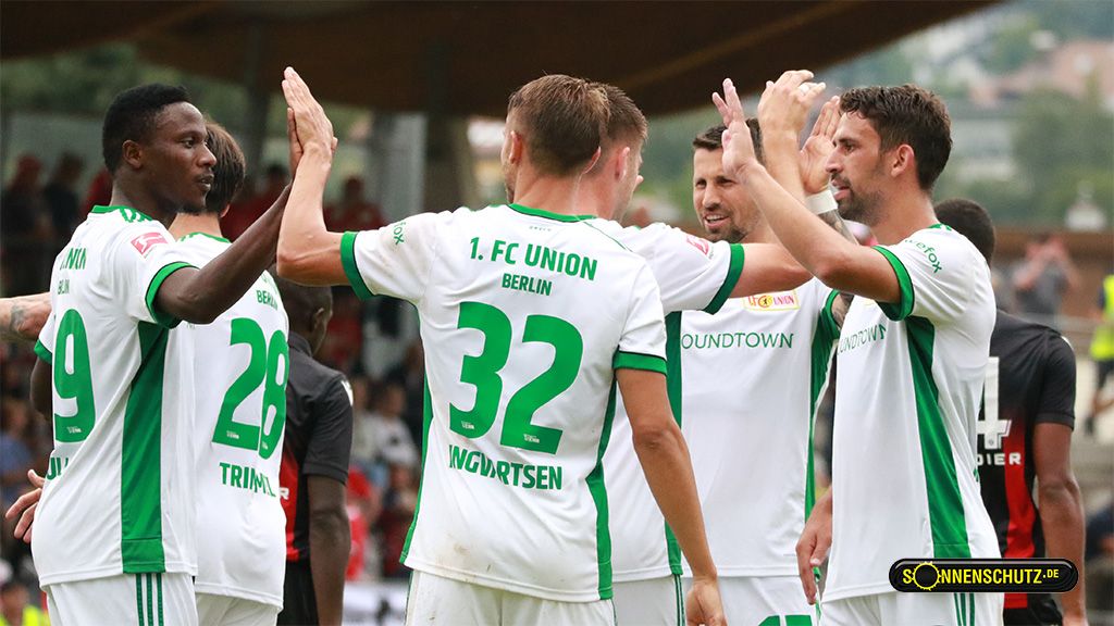 Spieler des 1. FC Union Berlin feiern einen Erfolg auf dem Spielfeld und geben sich gegenseitig High-Fives.
