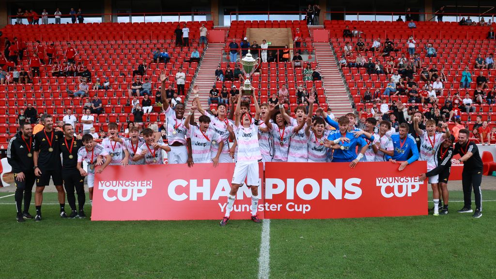 Jugendmannschaft feiert Sieg beim Youngster Cup, hebt die Trophäe in die Höhe, umgeben von jubelnden Spielern und Fans.
