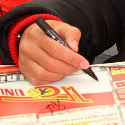 Eine Hand hält einen schwarzen Marker und schreibt auf einem Blatt Papier.