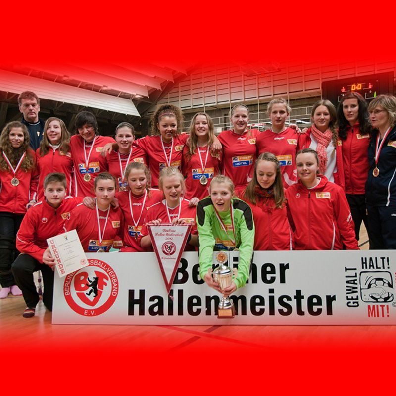 Gruppendbild von Fußballerinnen mit Medaillen, einem Pokal und einem Banner, das "Berliner Hallenmeister" zeigt.