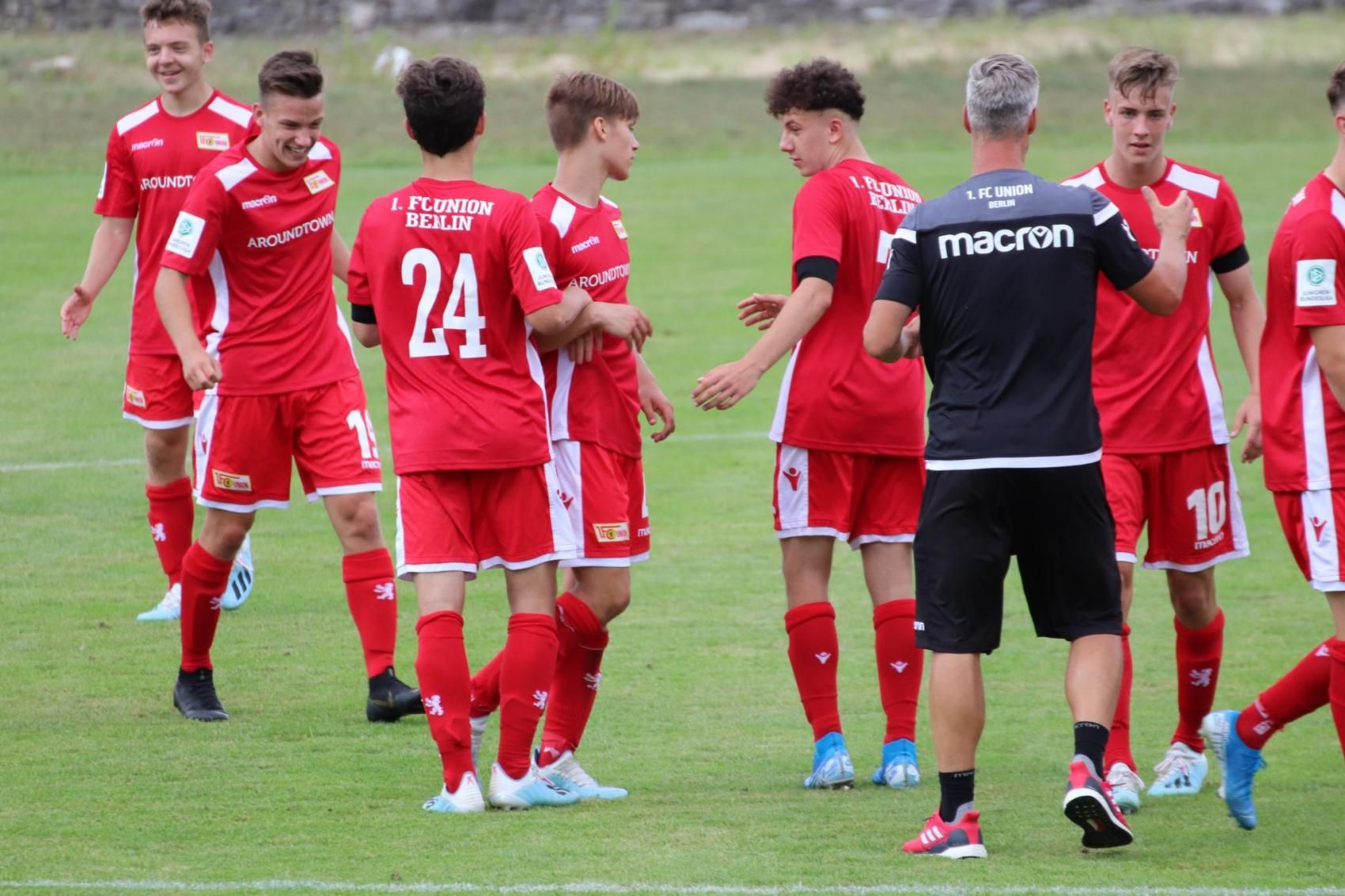 A group photo of football players in red jerseys, celebrating and interacting on the field.