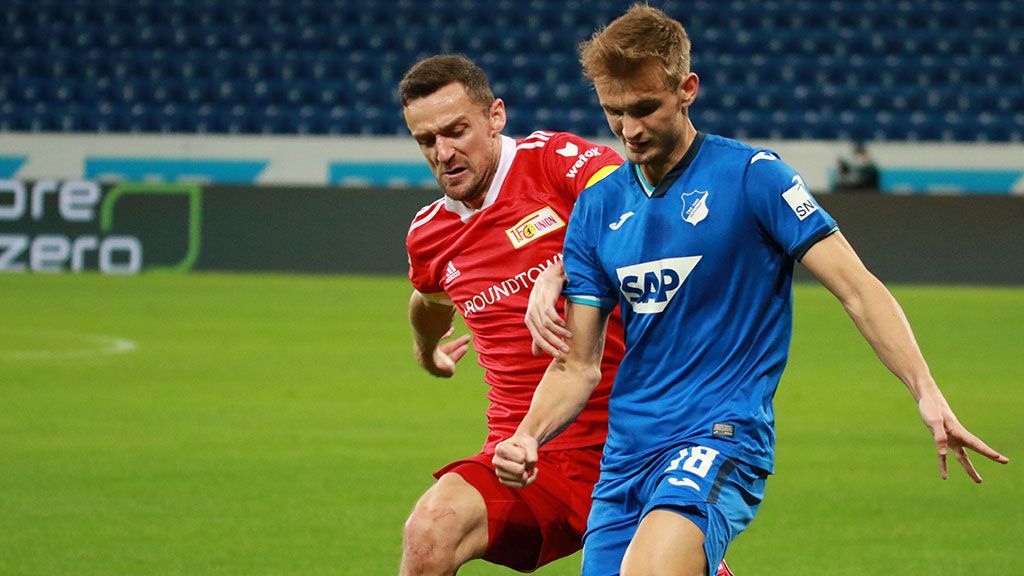 Zwei Fußballspieler kämpfen um den Ball auf einem grünen Spielfeld während eines Spiels.