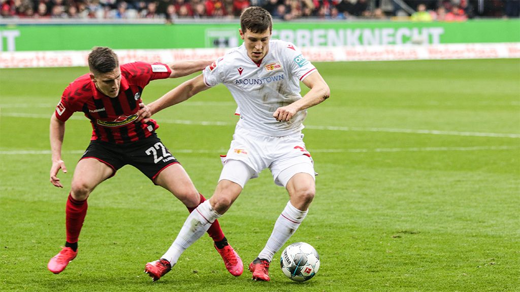 Two soccer players are fighting for the ball on a field during a game.