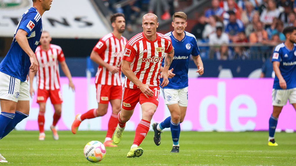 Two football teams in action during a game, with players in red, white, and blue jerseys.