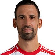 Ein lächelnder Mann mit kurzhaariger Frisur trägt ein rotes und weißes Sporttrikot.