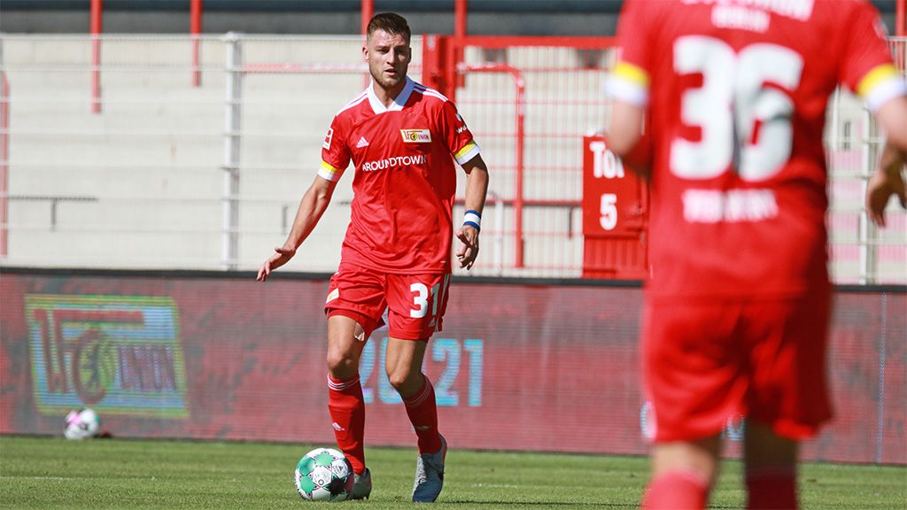 Spielszene: Ein Spieler in rotem Trikot mit der Nummer 3 steht mit einem Ball, während ein weiterer Spieler in der Nähe ist.