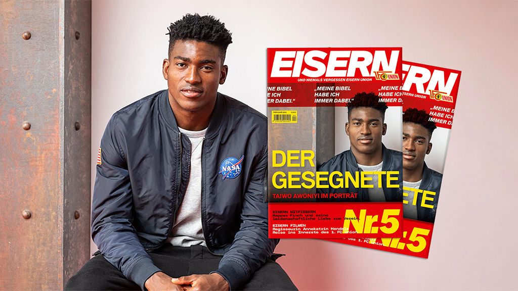 Ein junger Mann sitzt vor einer Wand und hält eine Zeitschrift mit dem Titel "EISERN" in der Hand.