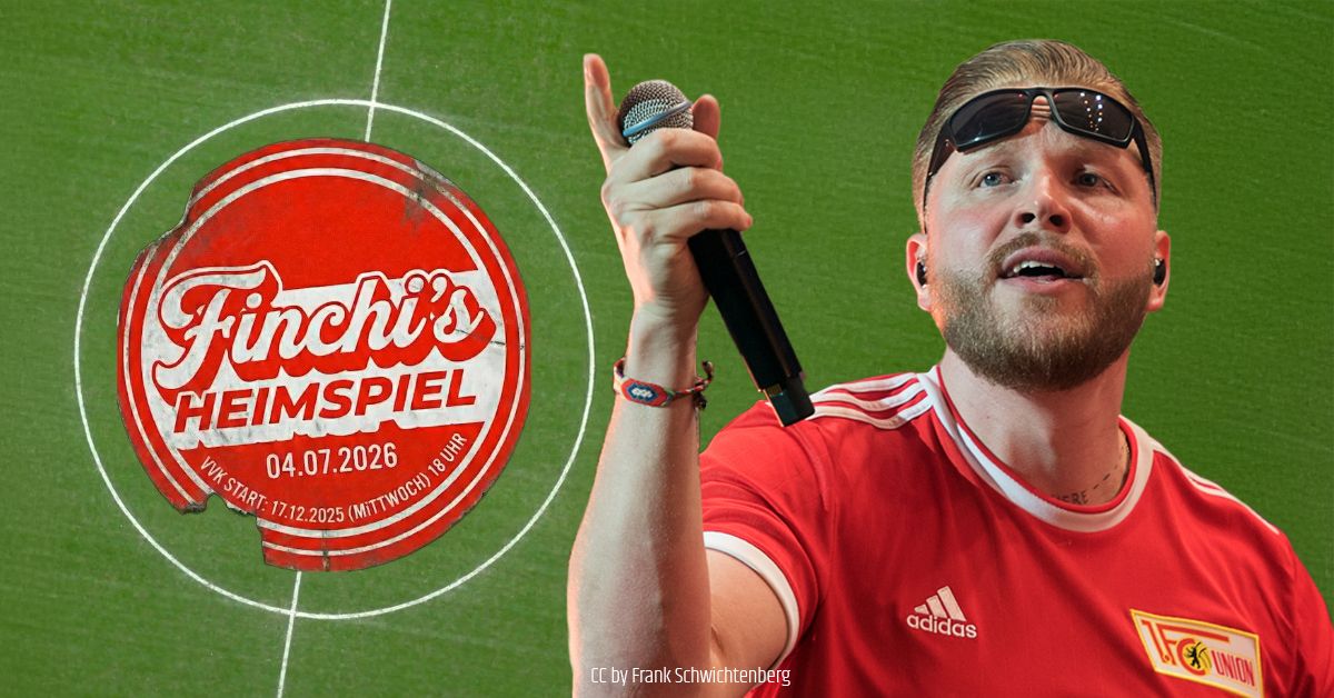 Mann mit Mikrofon und Sonnenbrille trägt ein rotes T-Shirt, im Hintergrund ein Logo für ein Event namens "Finchi's Heimspiel".