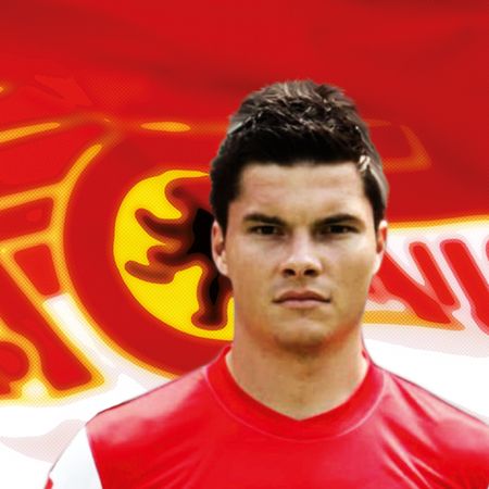 Ein Fußballspieler in einem roten Trikot mit einem auffälligen Hintergrund in rot und gelb.