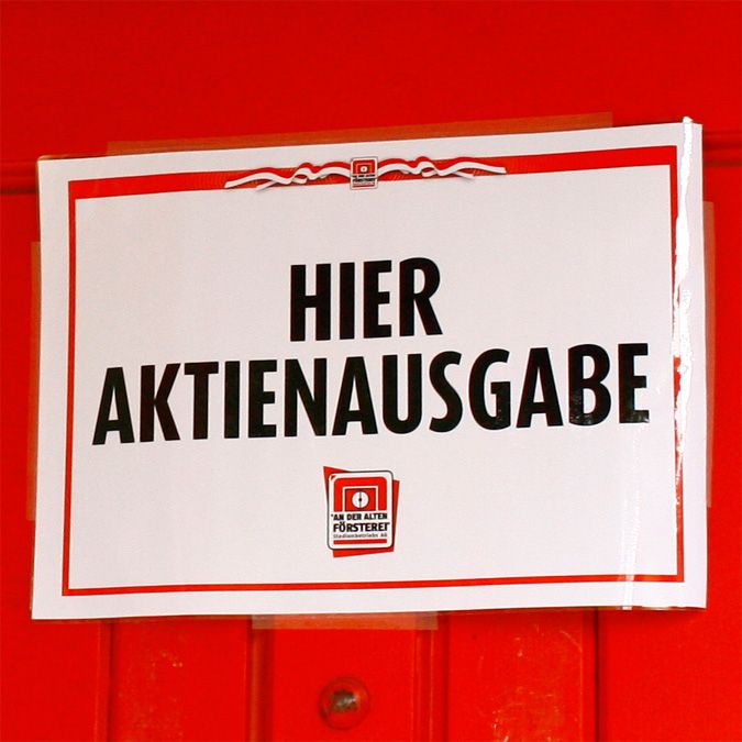 Ein Schild mit der Aufschrift "HIER AKTIENAUSGABE" auf rotem Hintergrund.