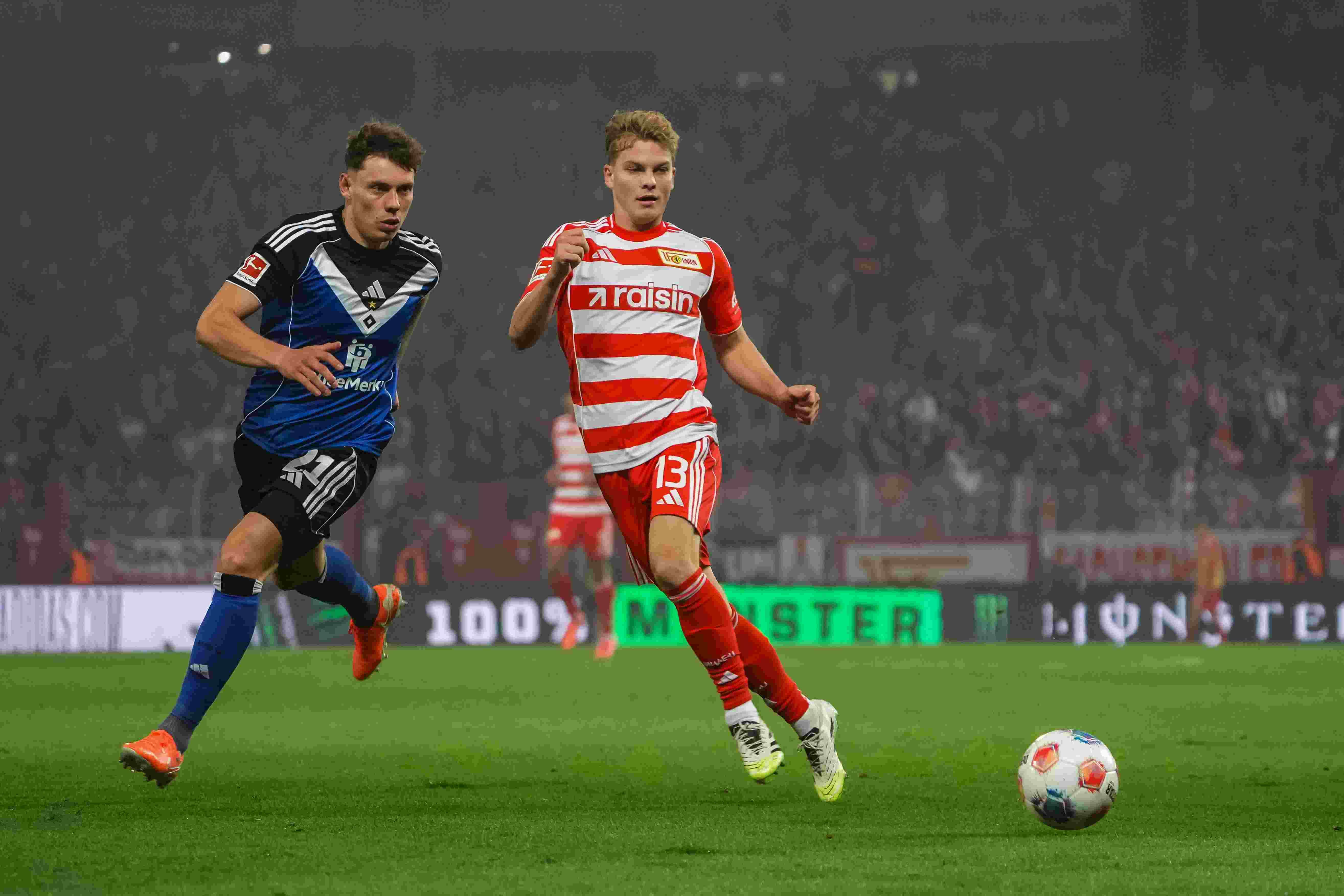 Zwei Fußballspieler im Wettlauf um den Ball während eines Spiels in einem Stadion.