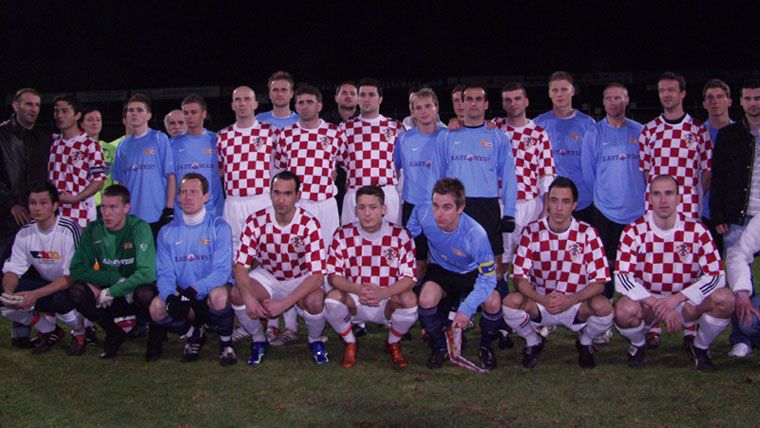Eine Gruppe von Fußballspielern in karierten Trikots stehen zusammen auf einem Spielfeld, um ein Teamfoto zu machen.