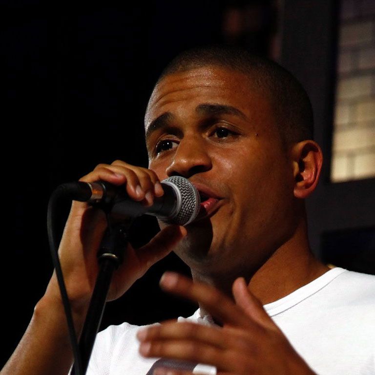 Ein Mann singt ins Mikrofon und gestikuliert dabei.