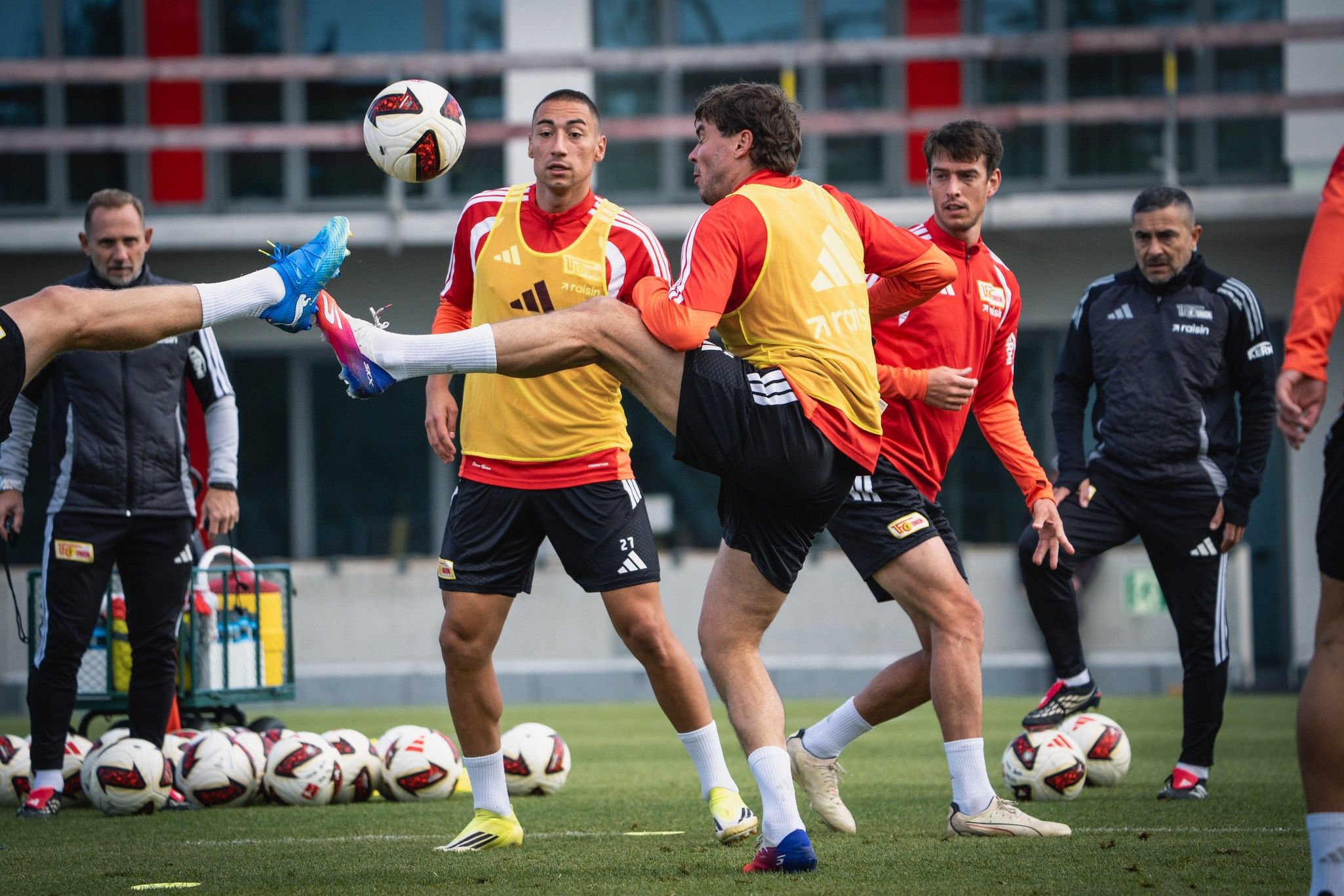 Fußballtraining mit Spielern in roten und gelben Trikots, die den Ball im Freien dribbeln und passen.