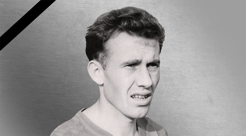 Ein Porträt eines jungen Mannes mit kurzem, lockigem Haar und einem nachdenklichen Gesichtsausdruck, vor einem schlichten Hintergrund.