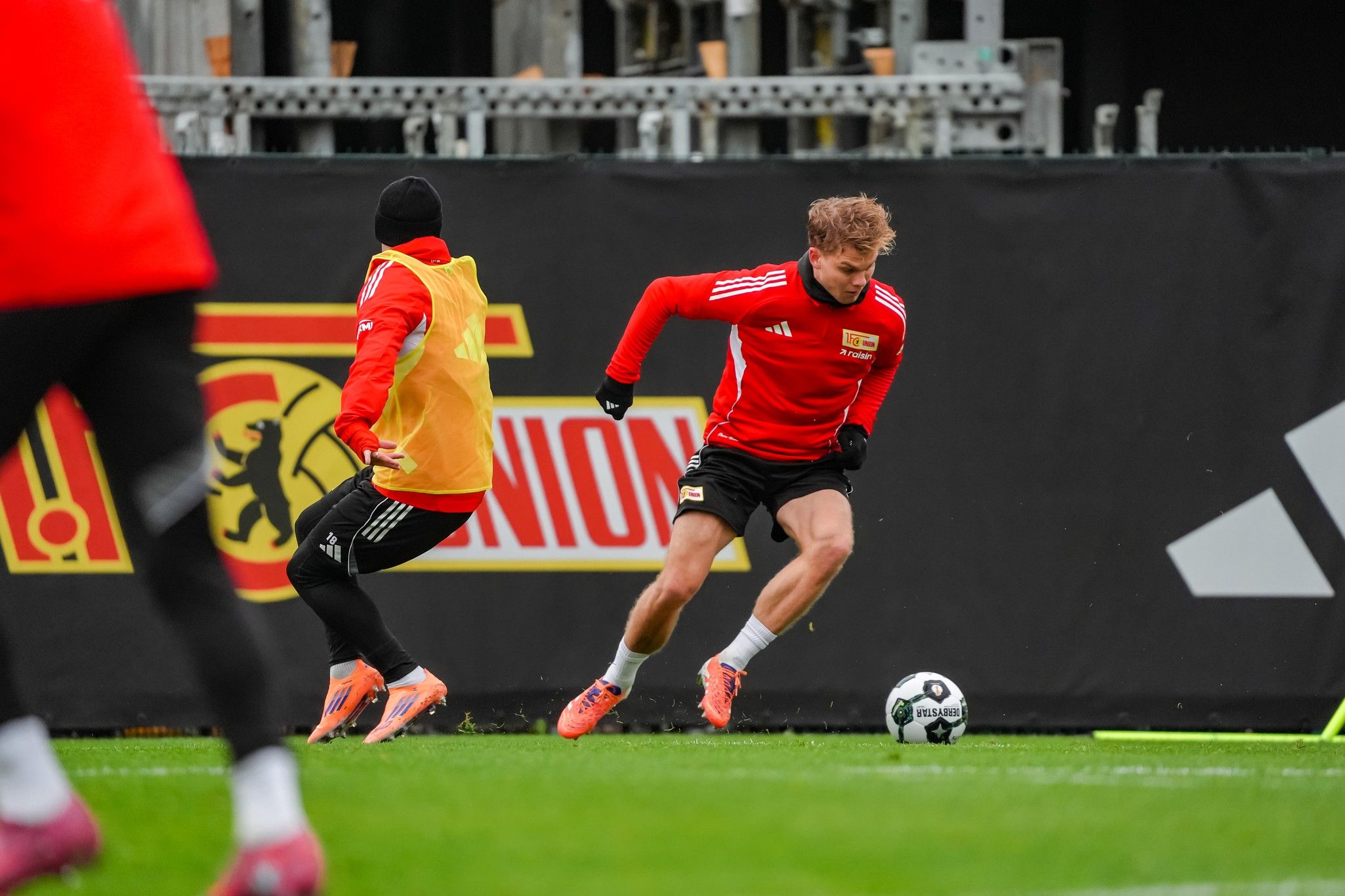 Zwei Fußballspieler im Training, einer dribbelt den Ball, der andere verfolgt ihn auf dem Feld.