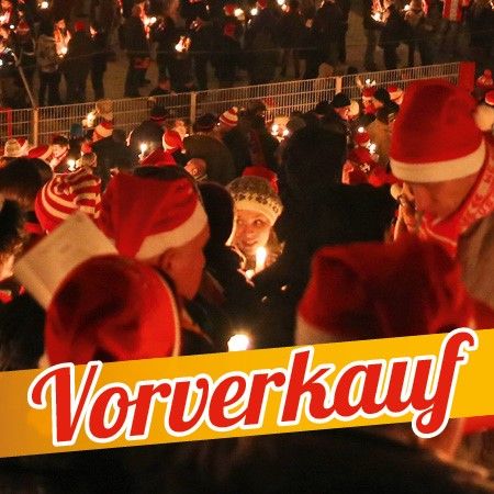 Menschenmenge mit Weihnachtsmützen, die Kerzen halten, bei einer festlichen Veranstaltung; im Vordergrund der Text "Vorverkauf".