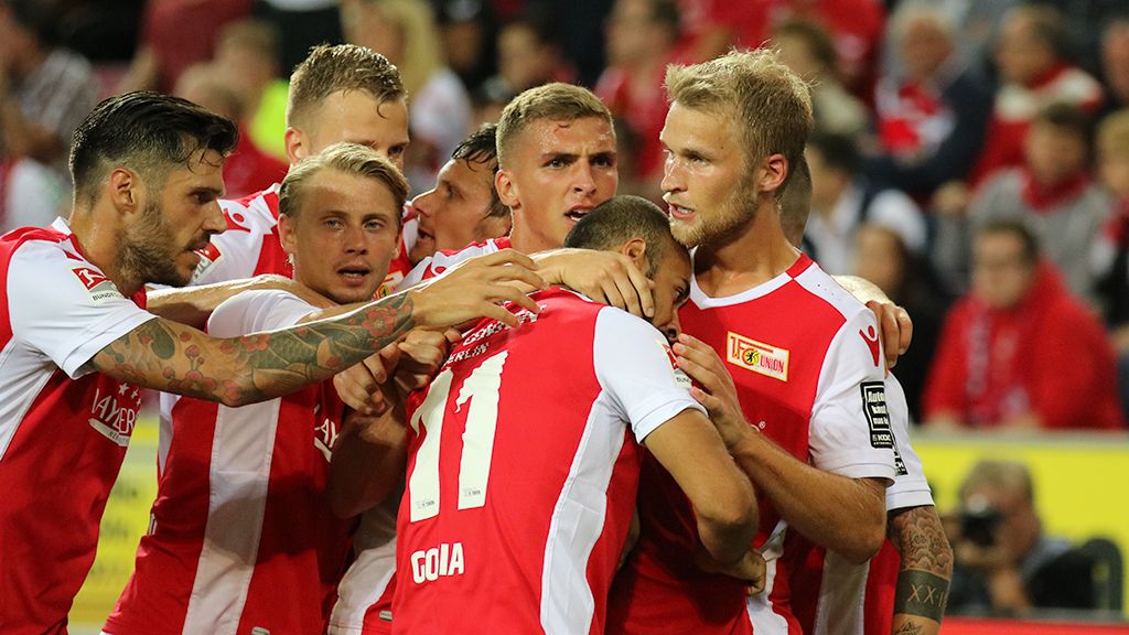 Die Spieler von Union Berlin freuen sich. Sie haben ein Tor geschossen. Sie feiern zusammen auf dem Feld.