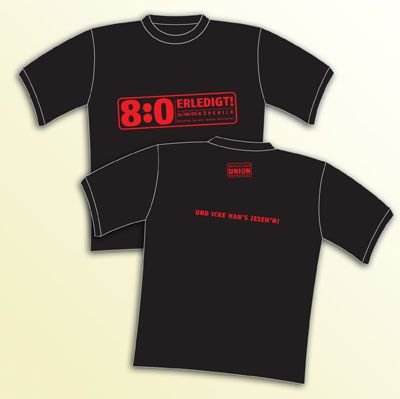 Schwarzes T-Shirt mit rotem Aufdruck: "8:0 ERLEDIGT!" auf der Vorderseite und "UND EICKI HAT'S JESEH'N!" auf der Rückseite.