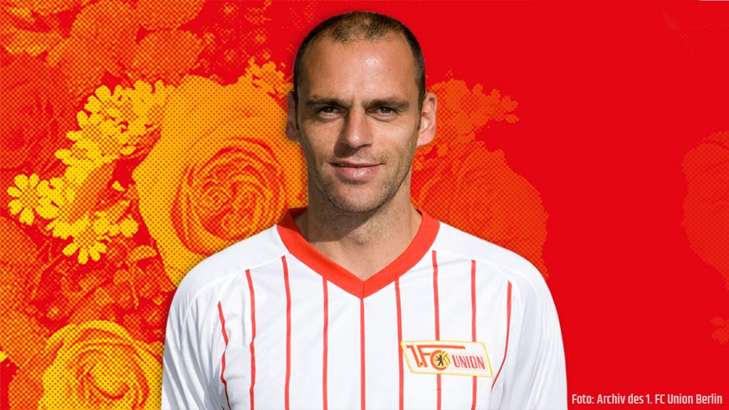 Ein Fußballspieler in einem weißen Trikot mit roten Streifen vor einem bunten Hintergrund mit Blumenmotiven.