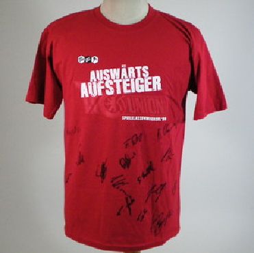 Rotes T-Shirt mit dem Aufdruck "AUSWÄRTS AUFSTEIGER" und mehreren Unterschriften.