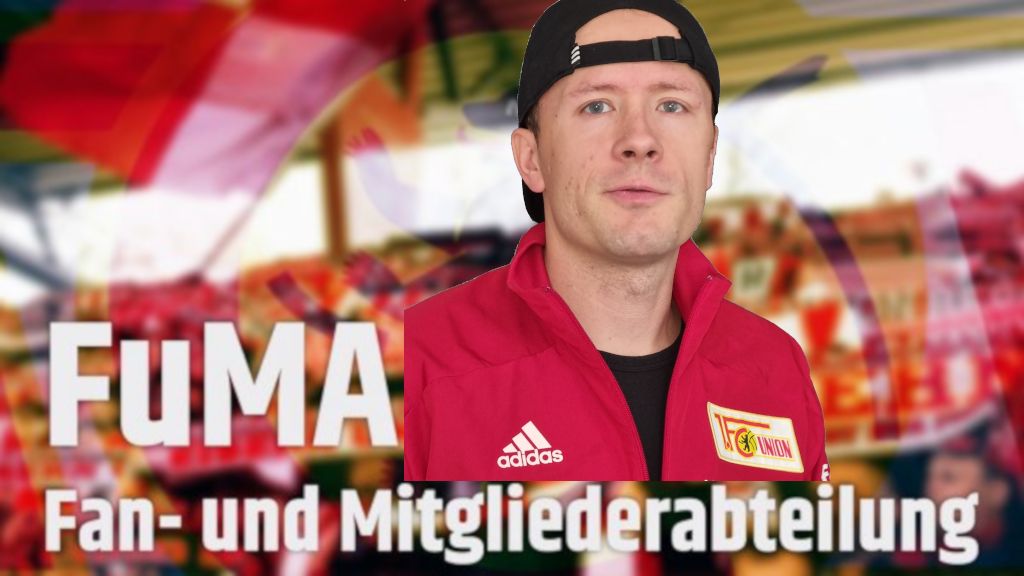 Mann in roter Jacke vor einer farbenfrohen Kulisse mit Schriftzug "FuMA - Fan- und Mitgliederabteilung".