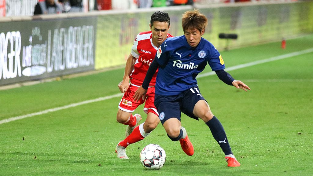 Zwei Fußballspieler kämpfen um den Ball auf dem Spielfeld während eines Spiels.