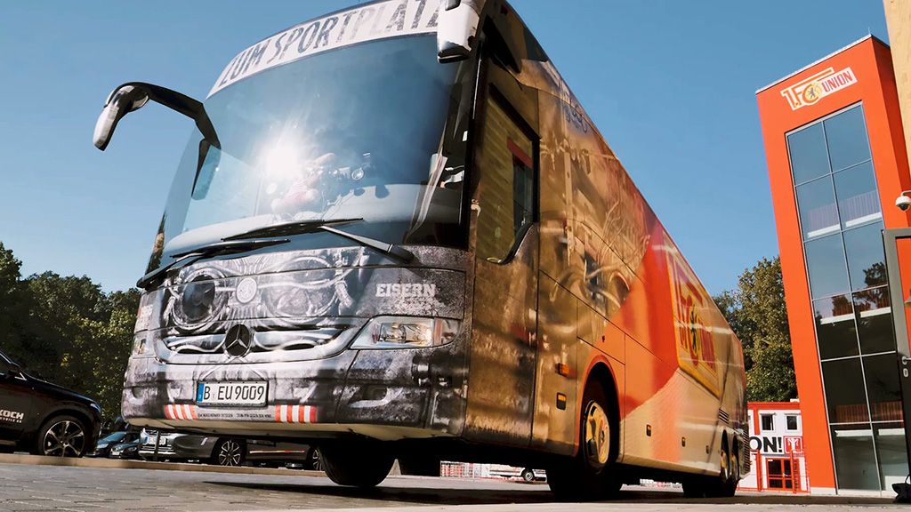 Ein farbenfroher Reisebus mit einem sportlichen Design parkt vor einem modernen Gebäude.