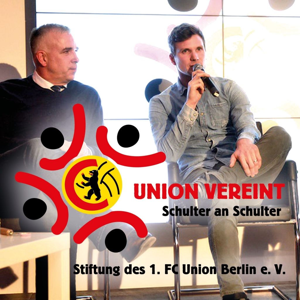 Zwei Männer sitzen auf Stühlen, sprechen ins Mikrofon, darüber ein Logo mit dem Text "UNION VEREINT - Schulter an Schulter".