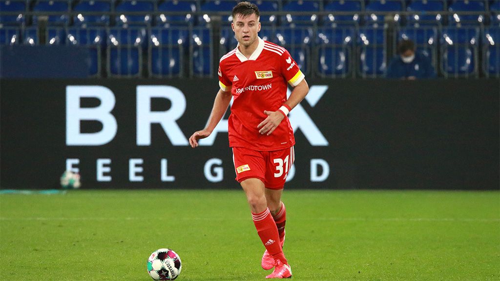 A football player in red with the number 31, wearing a captain's armband, is dribbling the ball on the field.