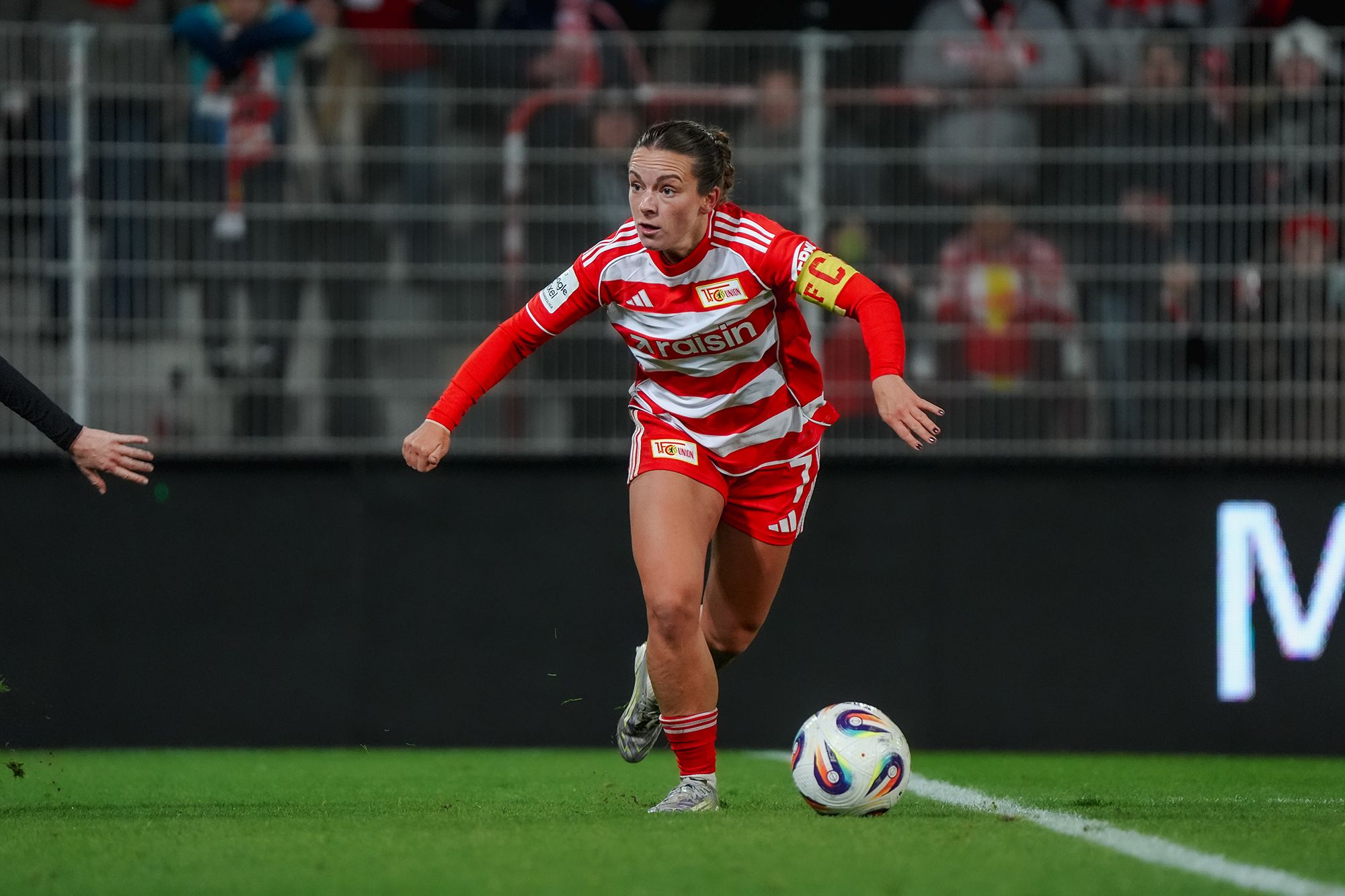 Eine Fußballspielerin in rot-weiß gestreifter Uniform sprintet mit dem Ball in Richtung Tor.