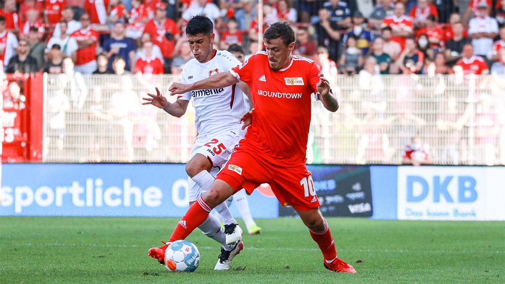 Zwei Fußballspieler kämpfen um den Ball während eines Spiels, der Spieler in Rot hat den Ball in Besitz.
