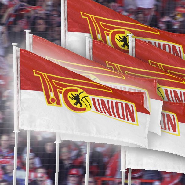 Fahnen mit dem Logo von FC Union wehen in einem Stadion voller Fans.