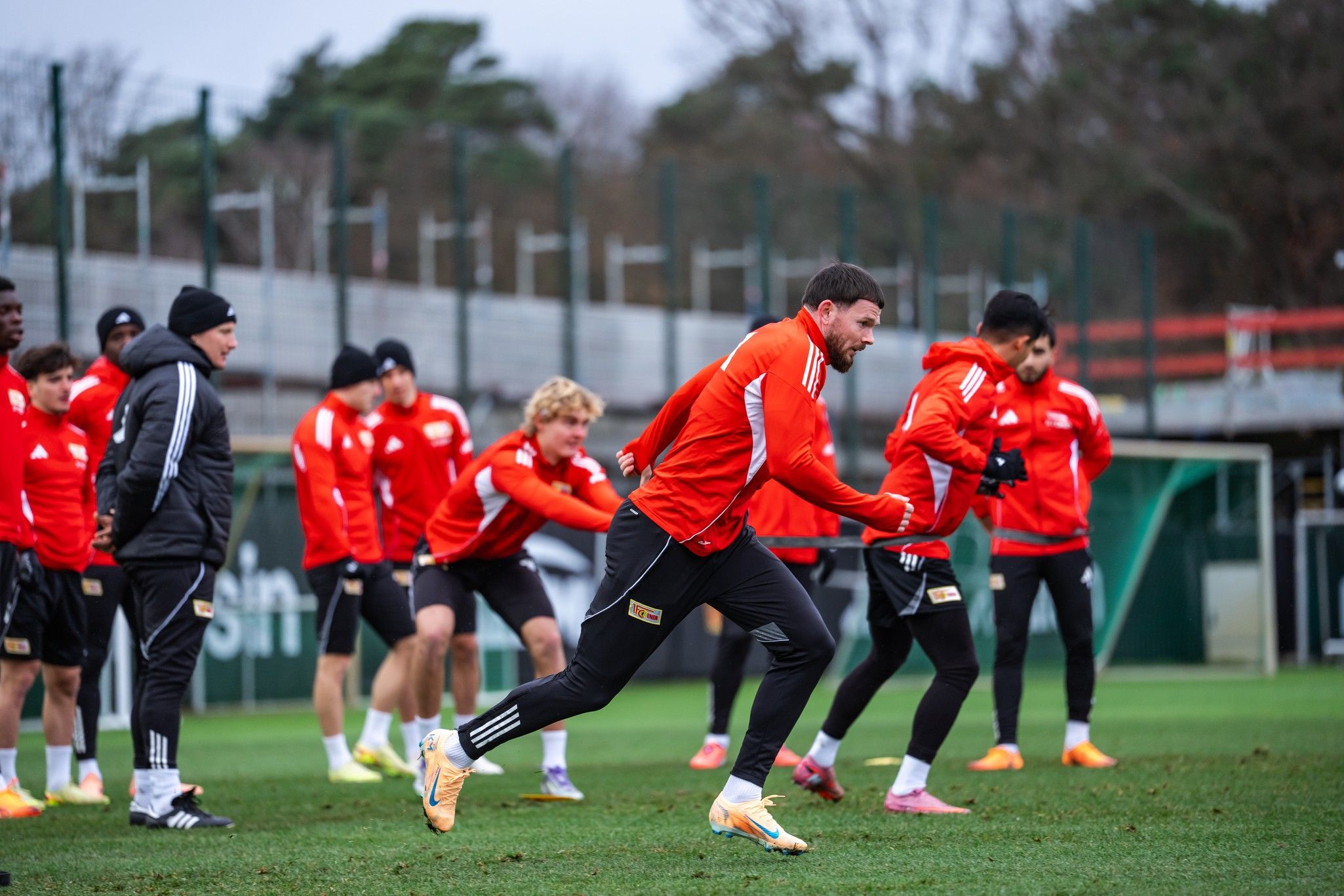 Fußballmannschaft in roter Trainingskleidung bei einer Übungseinheit auf dem Rasenplatz.